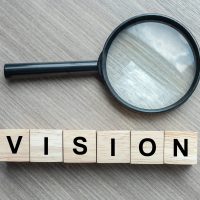 Vision text wooden cubes and magnifying glass on wood table back Vision text wooden cubes and magnifying glass on wood table background. SEO, Idea, Strategy, Analysis, goals and Values concept